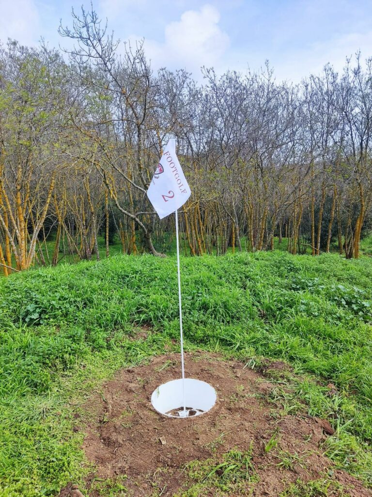 The footgolf hole, where players aim to kick their soccer ball into the cup at the end of each hole, marking the completion of their shot.